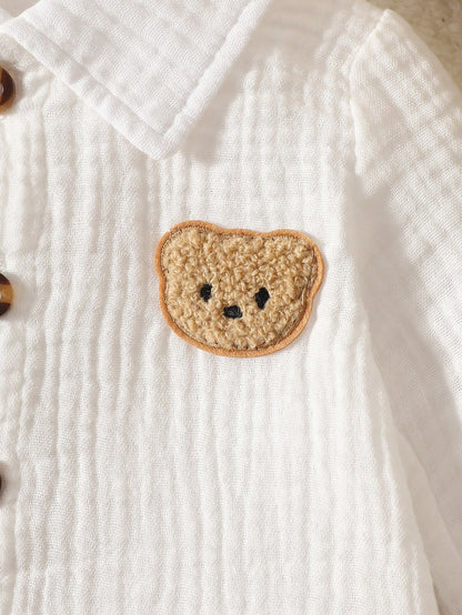 Newborn White Long-Sleeve Collared Shirt With A Small Bear Design, Paired With Apricot-Colored Pants